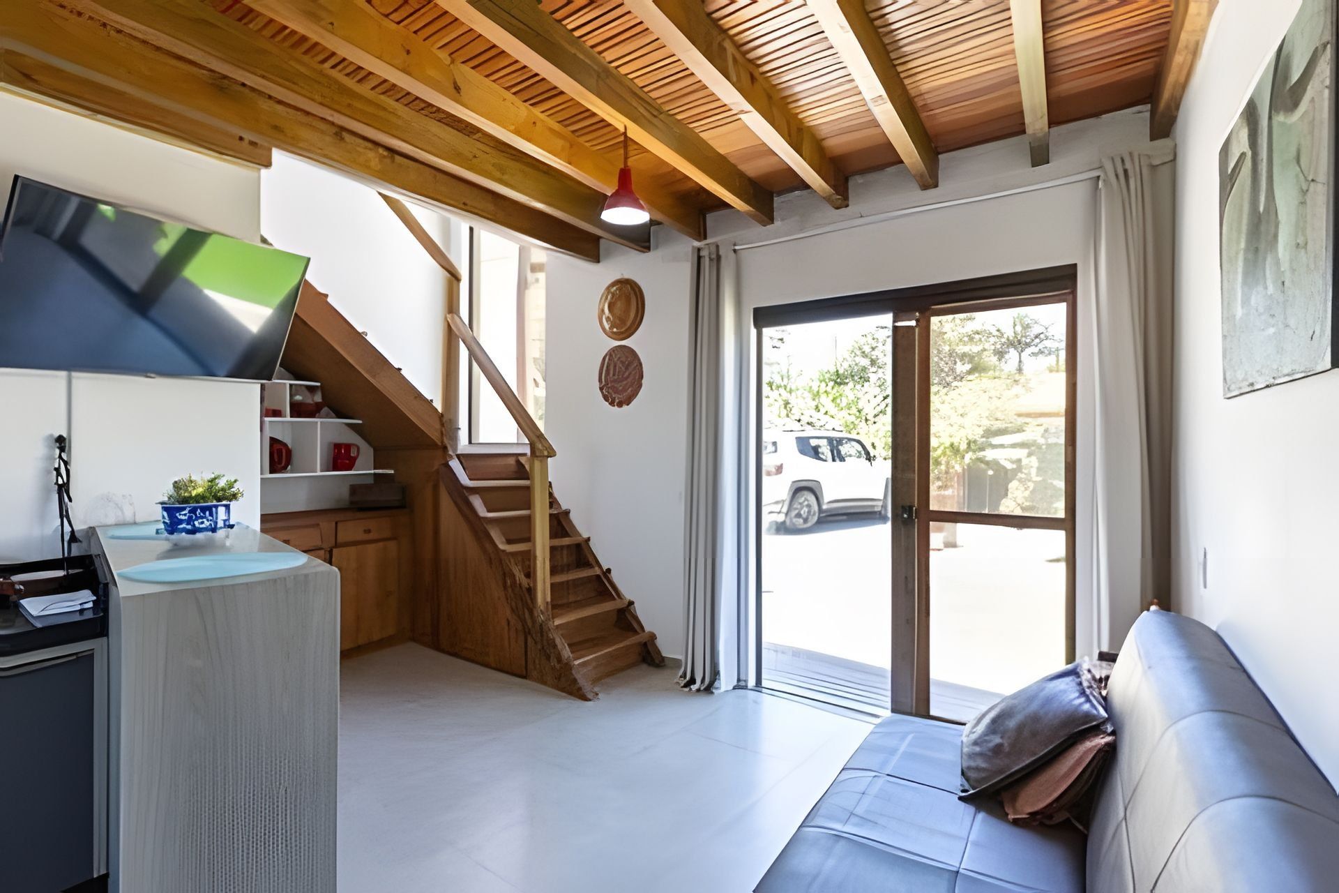 Eine moderne Küche mit einer Holztreppe, einem Essbereich mit einer Couch und einer großen Schiebeglastür zu einem Parkplatz.