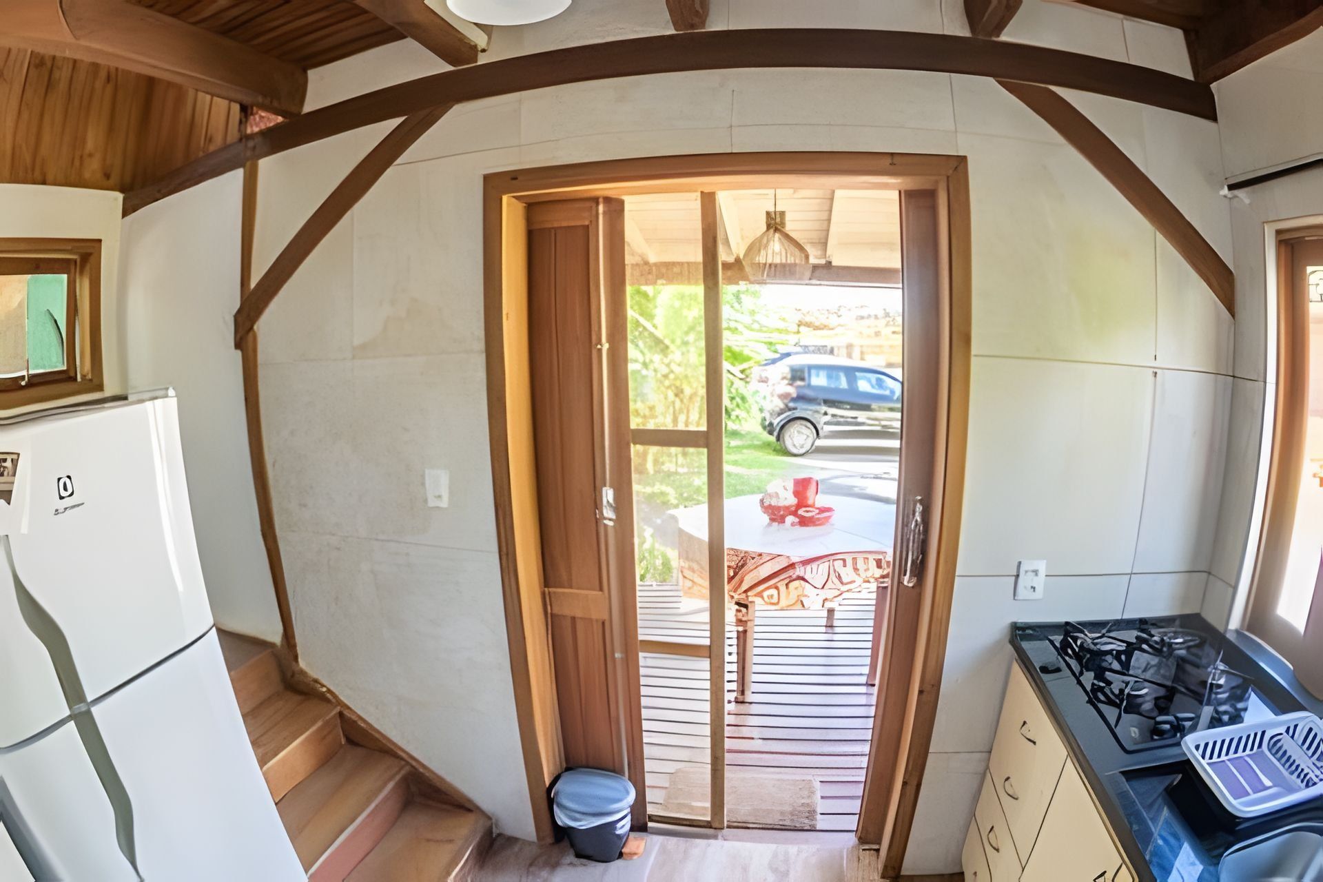 Una cocina con estufa a gas, refrigerador y puerta de madera que da a un patio.