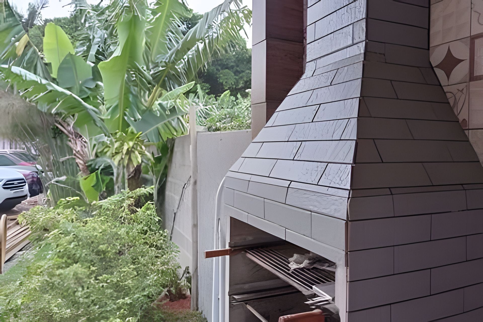 Un horno de ladrillo al aire libre con chimenea, rodeado de follaje.