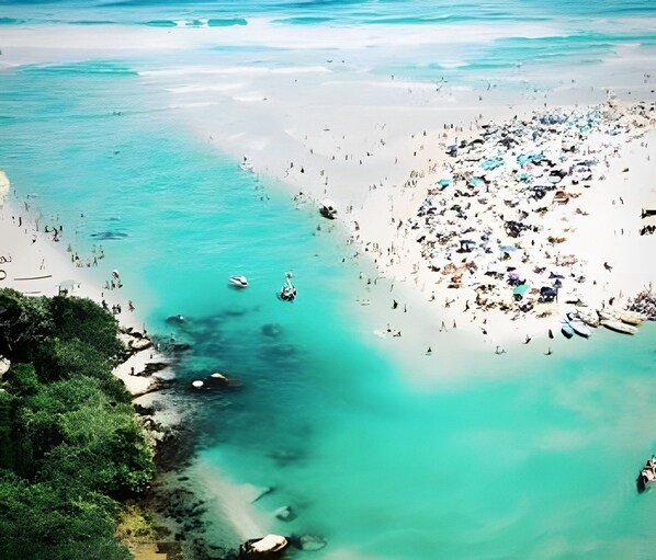 A beach with clear turquoise waters, a sandy shore, and several boats.