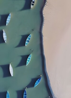 A beach with several boats anchored in shallow water.