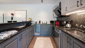 A modern kitchen with grey cabinets, a black countertop, and stainless steel appliances. - Luxe Bliss – 2BR, Glyfada (Glifada)