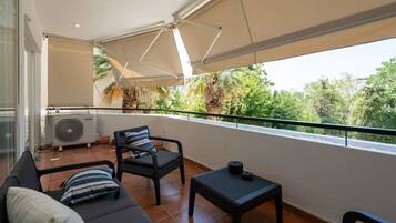 A balcony with a sofa, two chairs, a small table, and a ceiling fan.