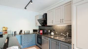 A modern kitchen with a central island, stainless steel appliances, and light blue cabinetry.