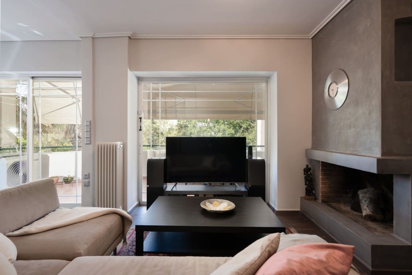 A modern living room with a flat-screen TV, a fireplace, and a sofa.