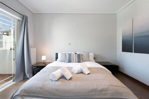 Ein Hotelzimmer mit einem großen Bett, einem Nachttisch, einer Lampe und Meerblick durch das Fenster.