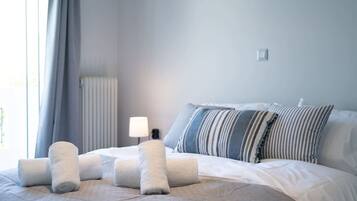 A hotel room with a bed, pillows, a lamp, and a radiator.