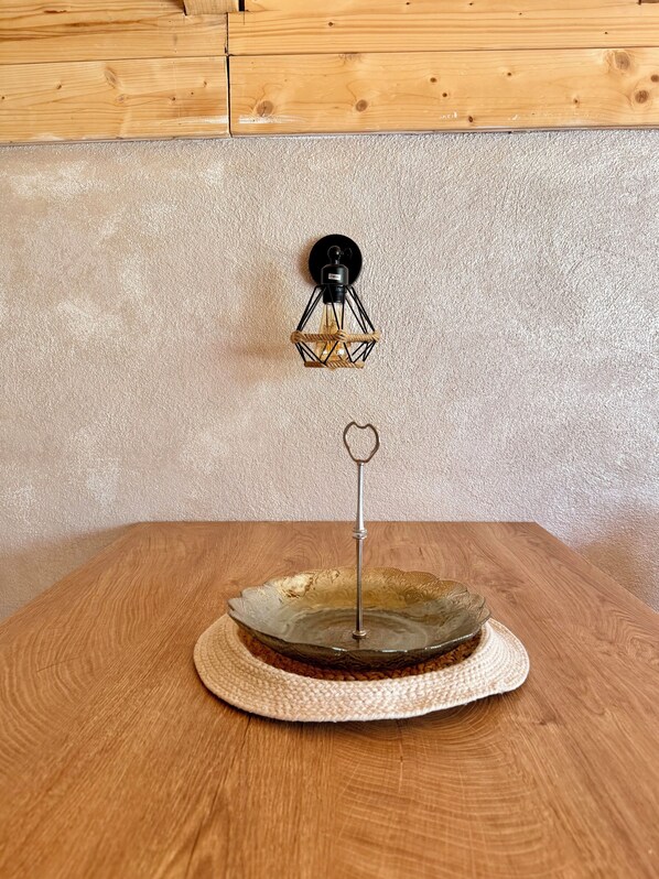 A wooden table with a decorative glass bowl and a metal stand with a heart-shaped ornament.