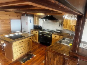 Eine kleine Küche mit Holzausstattung, einem Herd und einem Kühlschrank.