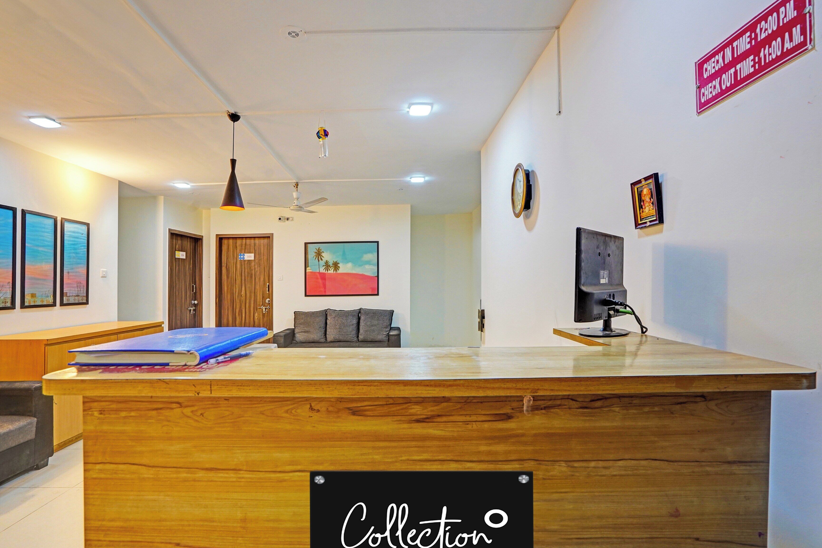A reception desk with a sign indicating check-in and check-out times, a ceiling fan, a painting on the wall, and a television on a stand.