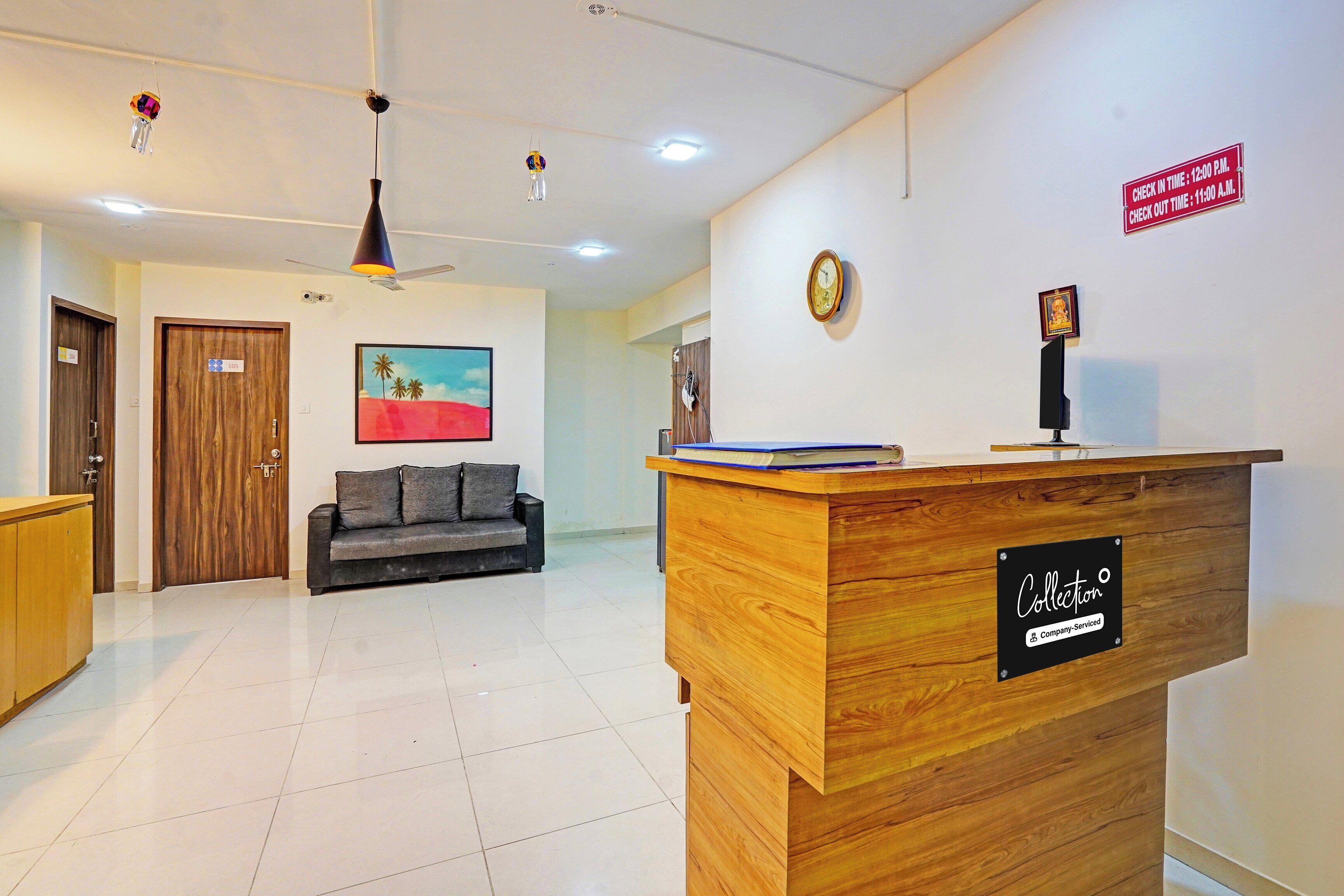 A hotel reception area with a wooden reception desk, a sofa, a painting, and a clock on the wall.