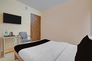 A hotel room with a bed, a desk with a chair, a television, and a wardrobe. - Super Collection O Baner Hillview Pune (Pune)