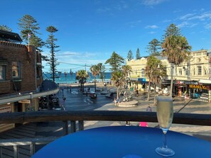 A coastal view with a clear sky, a beach, and a restaurant with outdoor seating.