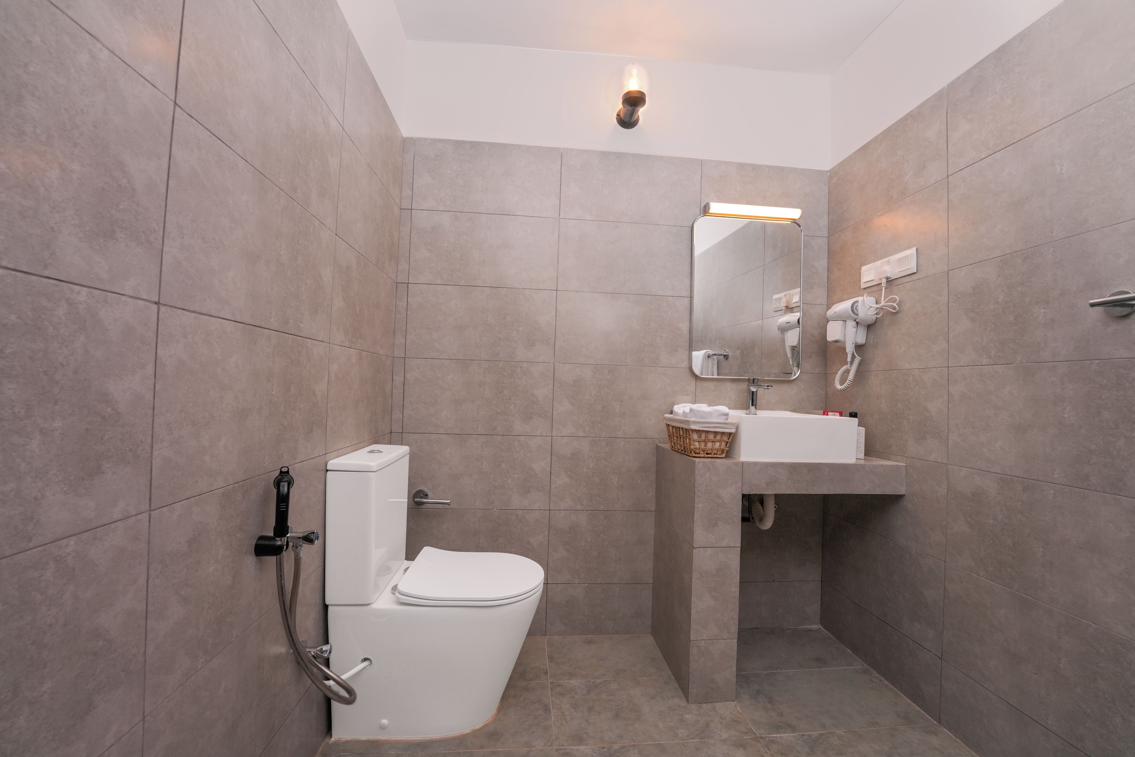 A modern bathroom with a toilet, bidet, and a sink with a mirror above it.