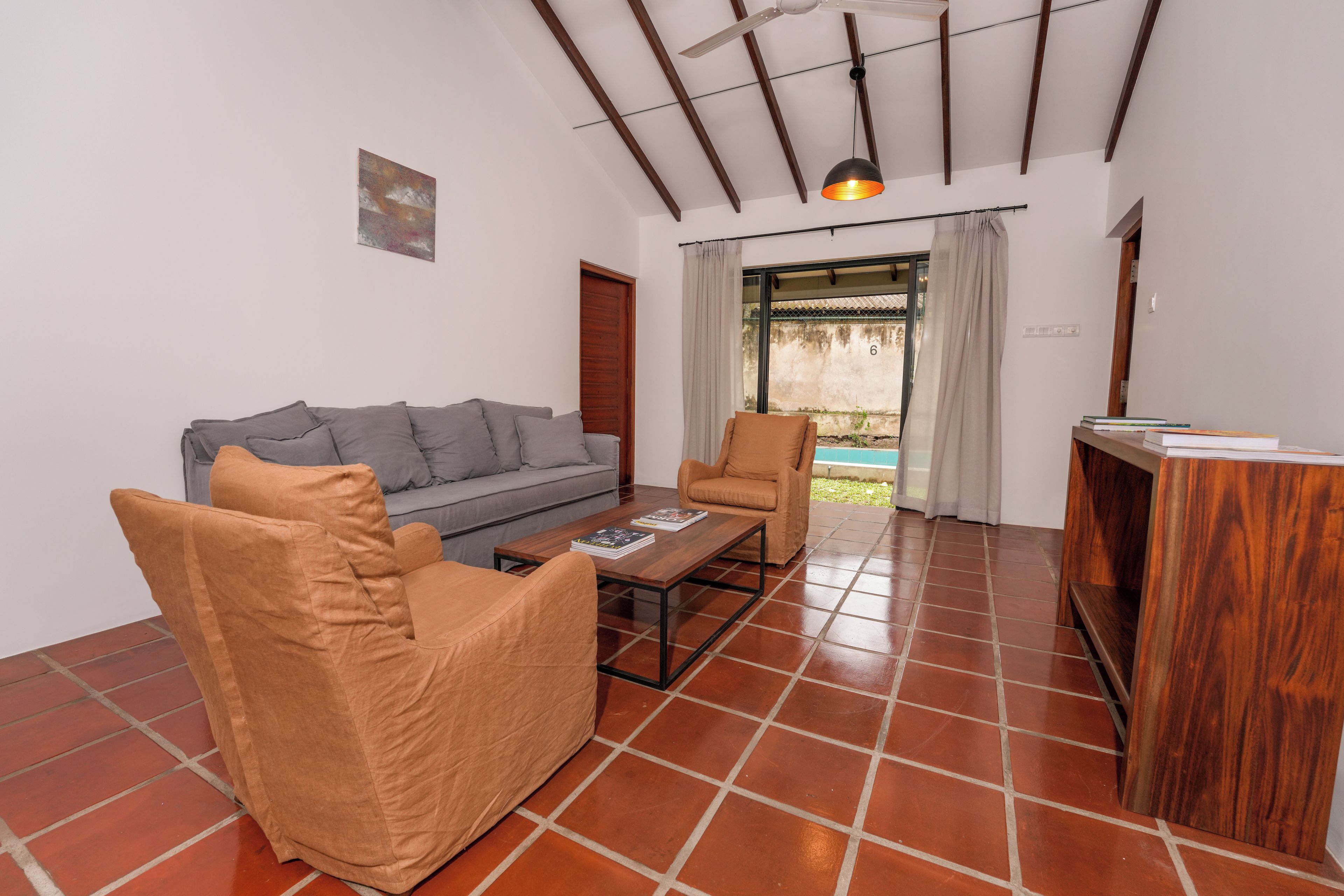 Una sala de estar con sofá, sillón, mesa de centro y una pequeña mesita de madera.