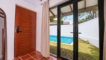 Quarto com porta de vidro deslizante que dá para um quintal com piscina.