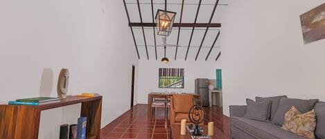 A modern living room with a wooden ceiling, a dining area, and a sofa.