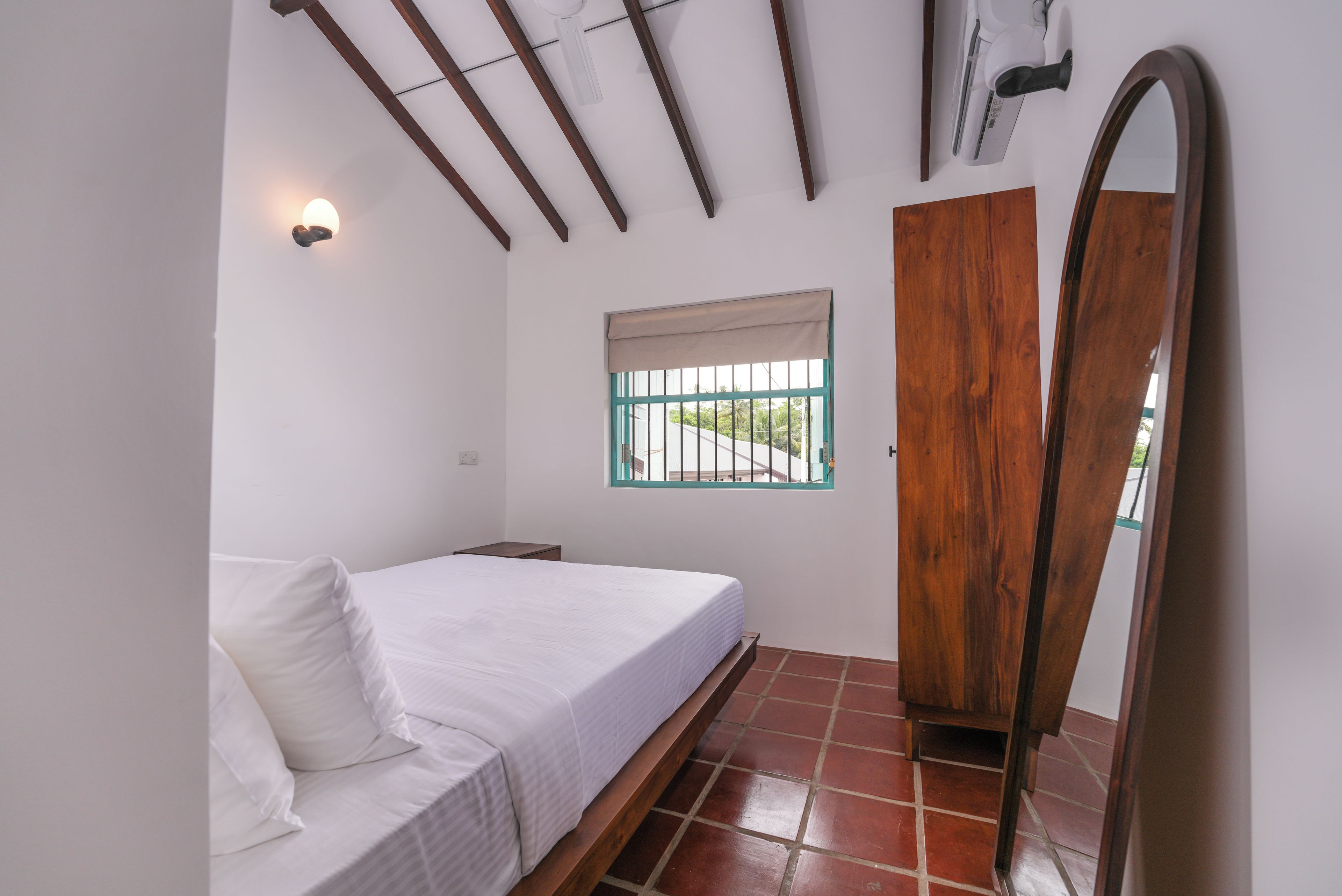 Ein Schlafzimmer mit Bett, Fenster mit Blick, Kleiderschrank und Deckenventilator.