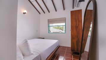 Quarto com cama, janela com vista, guarda-roupa e ventoinha no teto.