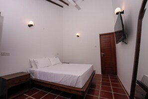 A bedroom with a bed, bedside tables, a wooden door, and two wall-mounted light fixtures.