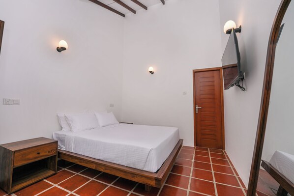 A bedroom with a wooden bed, white bedding, a wooden nightstand, and two wall-mounted lights.