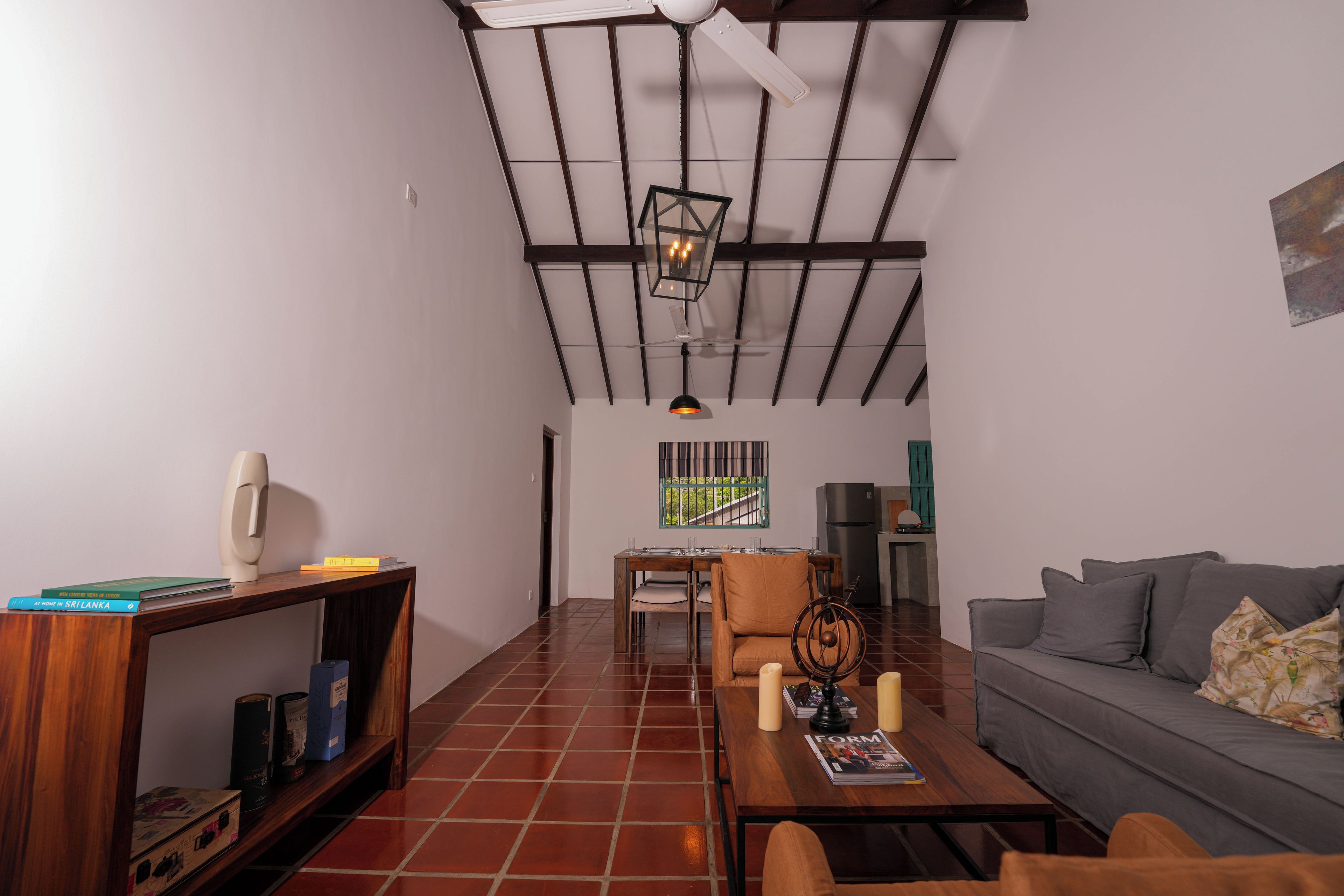 A spacious living room with a high ceiling, a dining area, and a sofa.