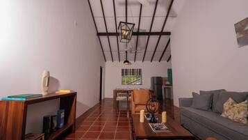 A spacious living room with a high ceiling, a dining area, and a sofa.