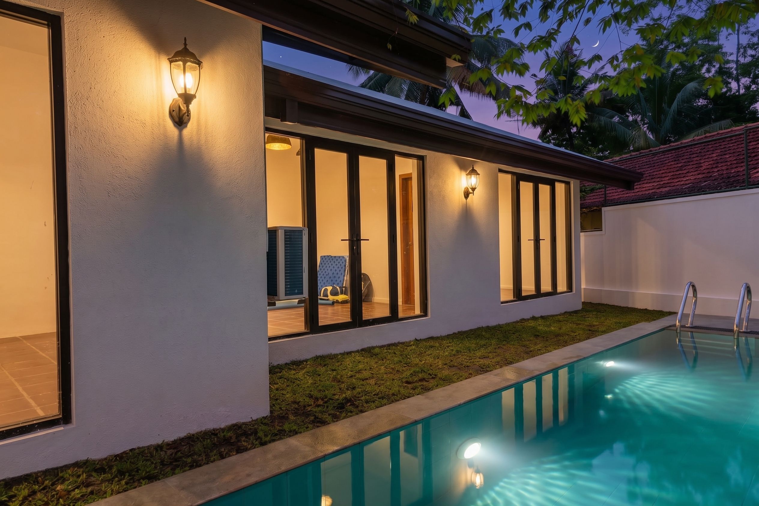Une maison moderne dotée d’une piscine, d’un éclairage extérieur et offrant une vue sur le ciel.