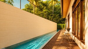 A swimming pool adjacent to a building with a white exterior wall and wooden window frames. - Honey Bee Collection Ahangama (Ahangama)
