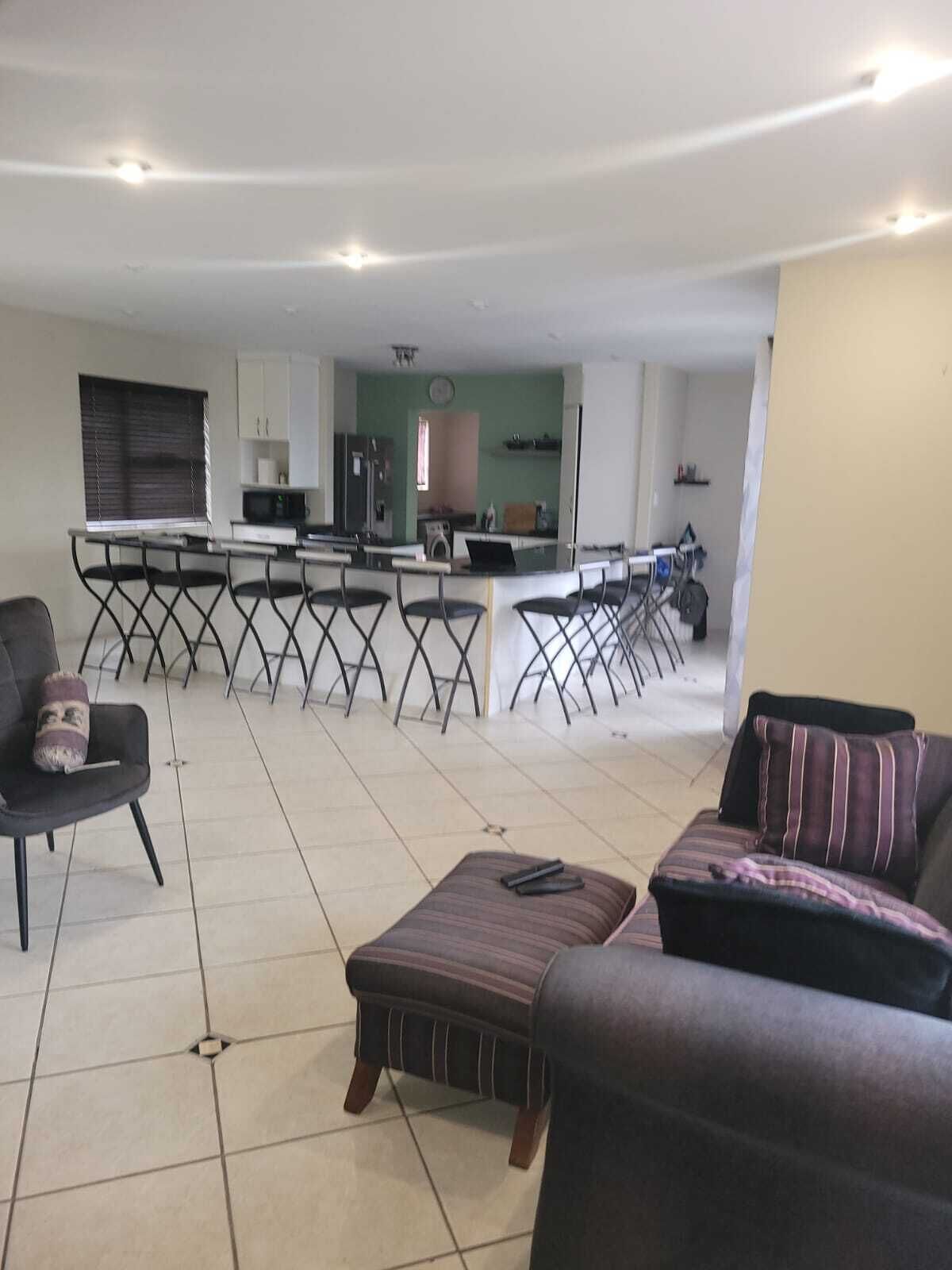 A living room with a sofa, a coffee table, and a dining area with a kitchen in the background.