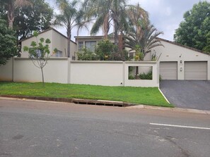 Ein Wohngebäude mit Garage, kleinem Garten und befestigter Auffahrt.