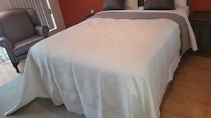 Una camera da letto con un letto, una sedia e una finestra con tende.