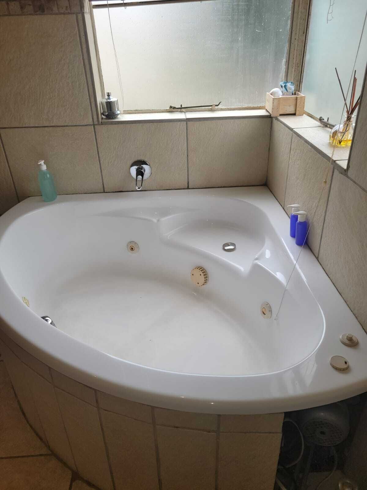 Une salle de bain avec une baignoire, une fenêtre et un mur carrelé.