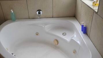 Une salle de bain avec une baignoire, une fenêtre et un mur carrelé.