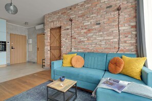 A living room with a blue sofa, wooden coffee table, and a brick wall. - Bastion Wałowa 49 | City Center | Parking (Gdańsk)