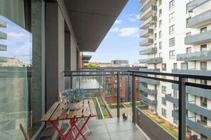 A balcony with a table and potted plants, overlooking a courtyard with a building in the background. - Bastion Wałowa 49 | City Center | Parking (Gdańsk)