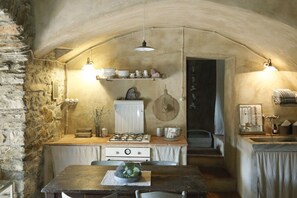 Une cuisine rustique avec des murs en pierre, une table en bois et une cuisinière à gaz.