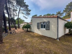 Ein kleines Gebäude mit einem Ziegeldach, einem Fenster mit Rollläden und einem Fahrrad davor.