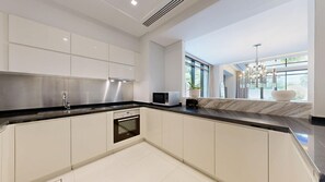 Eine moderne Küche mit weißen Schränken, einer schwarzen Arbeitsplatte und einem eingebauten Backofen.