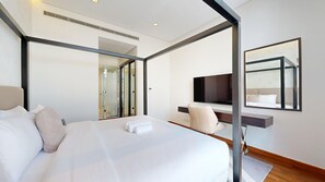 Ein modernes Hotelzimmer mit einem großen Bett, einem Schreibtisch mit Stuhl, einem Fernseher und einem Spiegel.