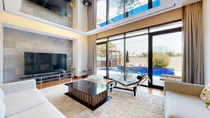 Ein modernes Wohnzimmer mit Flachbildfernseher, Glastisch und Lounge-Sessel.
