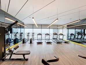 A gym with treadmills, exercise equipment, and large windows offering a city view. - Luxurious Studio l Prime Area l City View (Business Bsy)