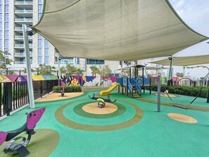 A children's play area with a slide, swings, and a climbing structure. - Luxe Studio in Prime Area l City View (Business Bsy)