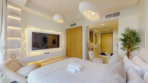 A modern hotel room with a large bed, a flat-screen TV, a seating area, and a small table. - Luxe Studio in Prime Area l City View (Business Bsy)