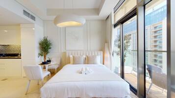 A hotel room with a large bed, a desk, and a view of the city through large windows.