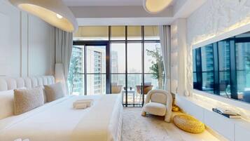 A modern hotel room with a large bed, a sitting area with a chair, and a large window offering a city view.