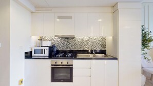 A compact kitchen with white cabinetry, a microwave, a stove, and a built-in oven. - Luxe Studio in Prime Area l City View (Business Bsy)