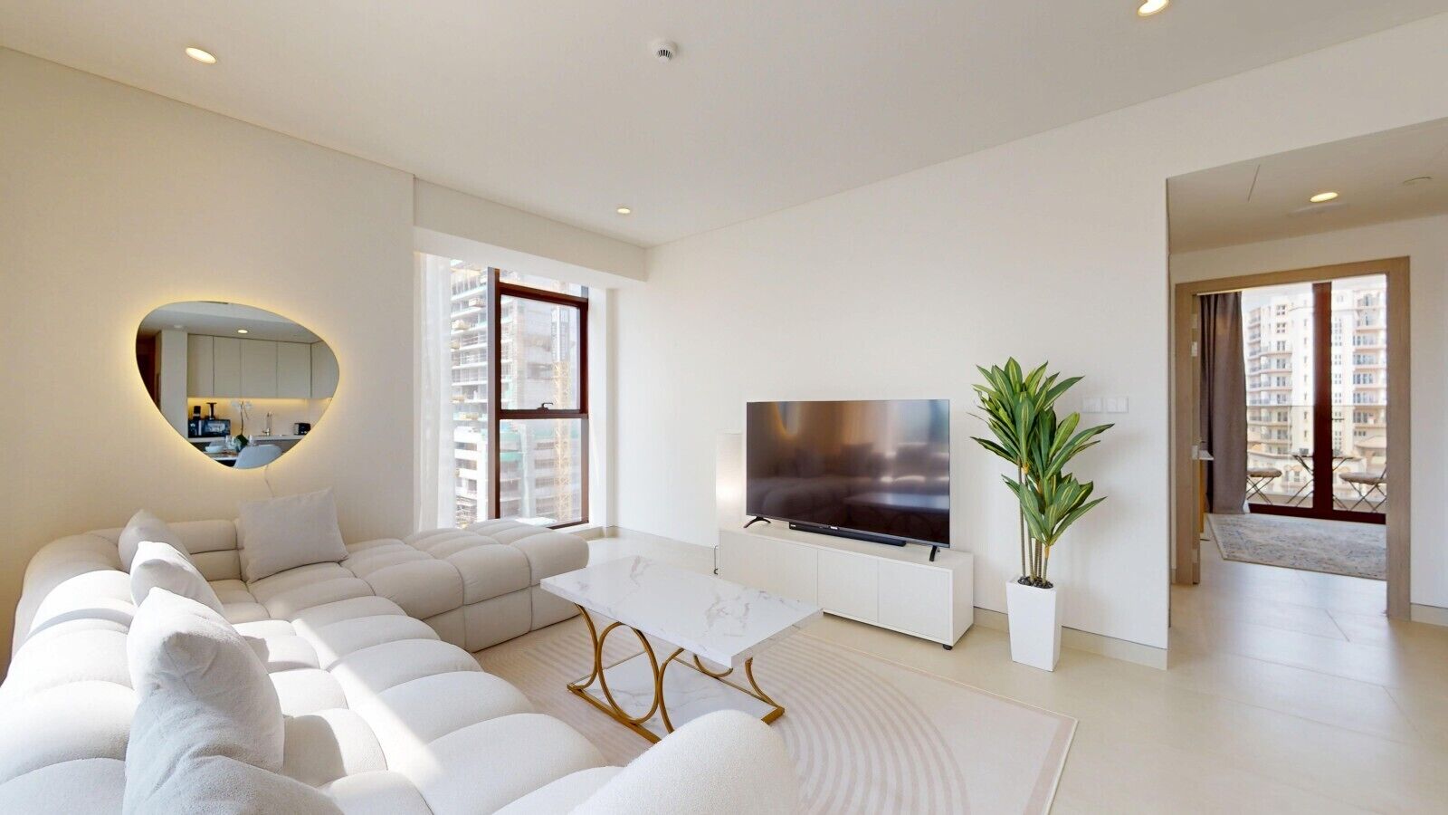 Un saló modern amb un sofà modular, una televisió de pantalla plana i una planta en test.