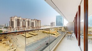Ein Balkon mit Blick auf eine Stadtansicht, darunter hohe Gebäude und eine Baustelle.