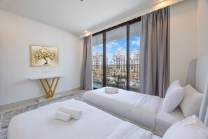Ein Hotelzimmer mit zwei Betten, Blick auf Gebäude, einem Gemälde an der Wand und einem kleinen Tisch.